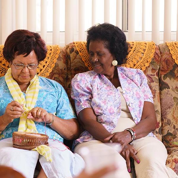 Two elderly ladies knitting on sofa